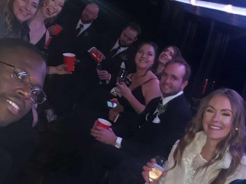 Group celebrating with glasses of champagne, inside of a party bus